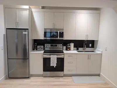 a kitchen with white cabinets and a stainless steel refrigerator at Delux 2 bedroom suite in White Rock