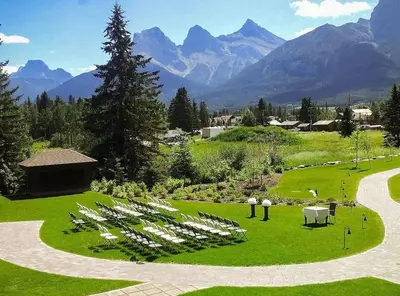 a garden with a bunch of white tables and chairs at Cozy Canmore resort with mt view hot tub and pool in Canmore