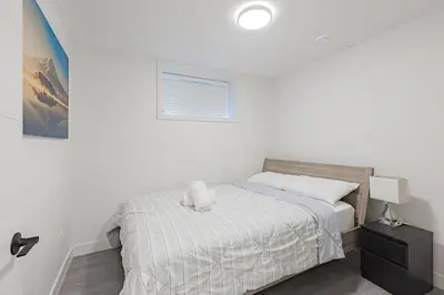 a white bedroom with a bed and a window at Dumfries Guest Room in Vancouver in Vancouver