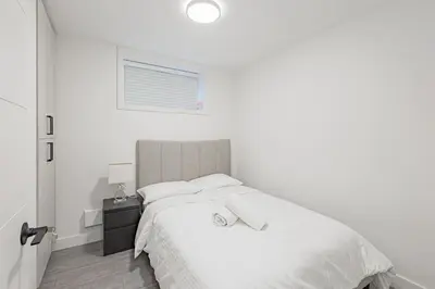 a white bedroom with a large bed with white sheets at Dumfries Guest Room in Vancouver in Vancouver