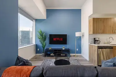 a living room with a kitchen and a blue wall at DT Edmonton King Suite with Parking & 100 Walk Score in Edmonton
