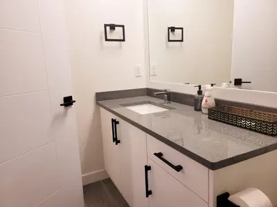 a bathroom with a sink and a mirror at Lovely Modern 2 Bedroom Basement Suite in Edmonton