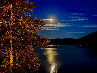 a full moon over a lake at night at Beachfront Lake House Moyie BC in Moyie