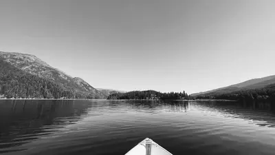 a boat on a lake with mountains in the background at Beachfront Lake House Moyie BC in Moyie