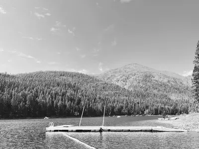 a boat on a lake with a mountain in the background at Beachfront Lake House Moyie BC in Moyie