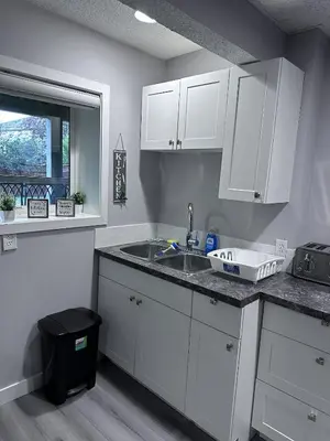 a kitchen with white cabinets and a sink and a window at Valley Gateway in Calgary