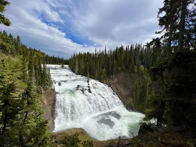 a waterfall in the middle of a forest at Tatogga Lake Resort in Iskut