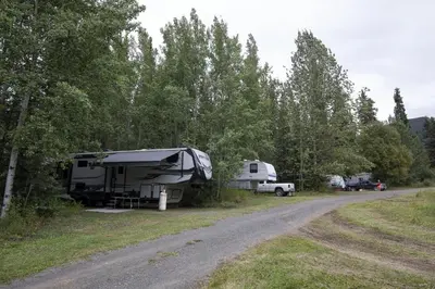 an rv and a truck parked next to a road at Tatogga Lake Resort in Iskut