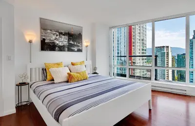 a white bedroom with a large bed and large windows at Luxury 2BR Designer Apartment In The Heart Of Downtown! in Vancouver
