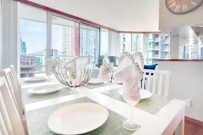 a dining room with a table with plates and glasses at Luxury 2BR Designer Apartment In The Heart Of Downtown! in Vancouver