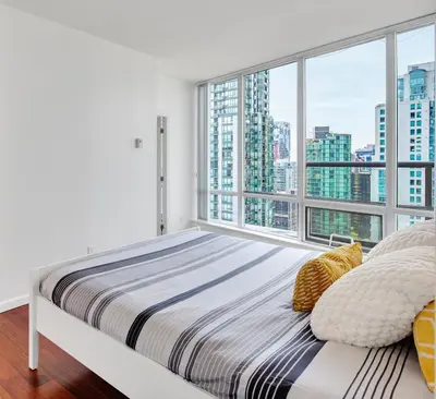 a bedroom with a bed and a large window at Luxury 2BR Designer Apartment In The Heart Of Downtown! in Vancouver