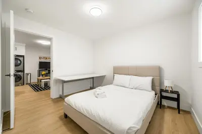 a bedroom with a white bed and a desk at A cozy and stylish 2-bedroom retreat in Surrey