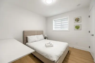 a white bedroom with two beds and a window at A cozy and stylish 2-bedroom retreat in Surrey