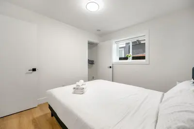 a white bedroom with a bed and a window at A cozy and stylish 2-bedroom retreat in Surrey