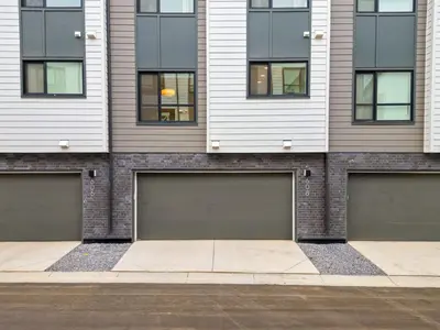 a building with four garage doors in front of it at 3 Bedroom Luxurious Seton Town Home with Central AC and Lake View in Calgary