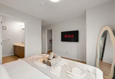 a white bedroom with a bed and a mirror at 3 Bedroom Luxurious Seton Town Home with Central AC and Lake View in Calgary
