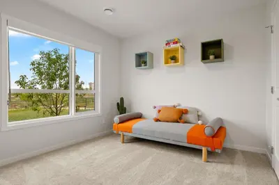 an orange couch in a white room with a window at 3 Bedroom Luxurious Seton Town Home with Central AC and Lake View in Calgary