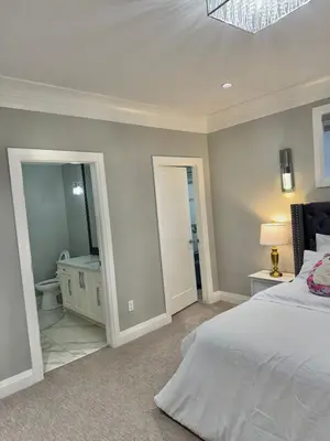 a bedroom with a bed and a bathroom with a mirror at Luxury Chestermere Retreat in Calgary