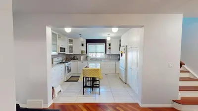 a kitchen with white cabinets and a table and stool at Cozy comfy and relaxing home at Cougaridge SW Calgary in Calgary