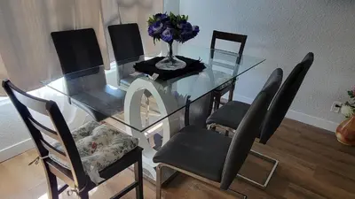 a glass dining room table with chairs and a vase of flowers at 3 Bedroom House Near Airport and Downtown in Calgary