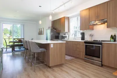 a kitchen with wooden cabinets and a table with chairs at Stylish Three Bedroom Townhome in Squamish
