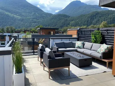 a patio with couches and chairs on a balcony with mountains at Stylish Three Bedroom Townhome in Squamish