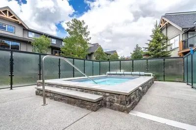 a hot tub in a patio with a fence at Best 2BR Canmore Stay, Banff, Wifi & Free Parking Incl in Dead Man's Flats