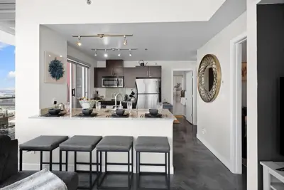 a kitchen and living room with a bar with stools at Urbanest - Spectacular Views & Amenities Parking in Calgary