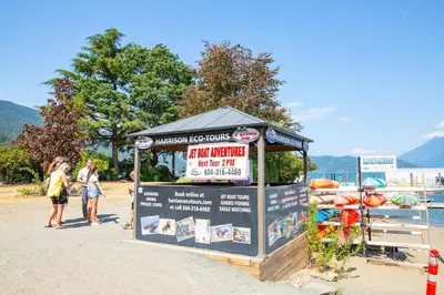 a kiosk on a beach with people standing around it at Studio w Balcony with Smart TV and 2 Min Walk to Lake in Harrison Hot Springs