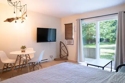 a bedroom with a bed and a table and a window at Studio w Balcony with Smart TV and 2 Min Walk to Lake in Harrison Hot Springs