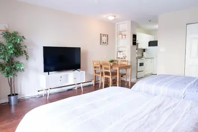 a bedroom with two beds and a flat screen tv at Beachy 2 Bed Studio Suite, Balcony and 4 Min to Lake in Harrison Hot Springs