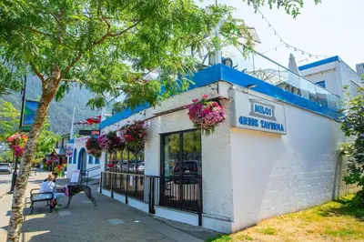 a woman sitting on a bench in front of a building at Beachy 2 Bed Studio Suite, Balcony and 4 Min to Lake in Harrison Hot Springs