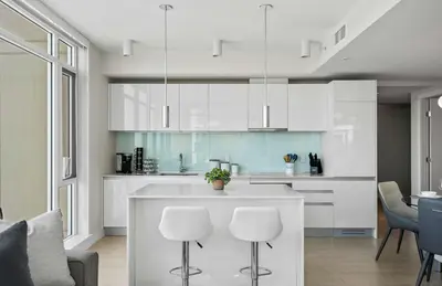 a kitchen with white cabinets and a kitchen island with stools at The Getaway Next to Stampede 2BR Suite Downtown in Calgary