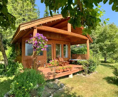 a log cabin with a porch and flowers in the yard at Wing Creek Resort in Kaslo