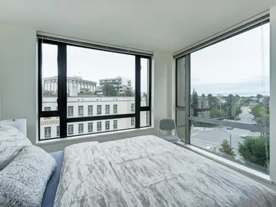 a bedroom with a bed and large windows at Astoria Escape - Bright condo with work desk by Victoria Prime! in Victoria