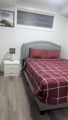 a bedroom with a bed with a red comforter at Cozy Escape Guest Suite in Edmonton