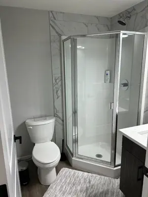 a white bathroom with a shower and a toilet at Bright & Spacious 2BR Getaway in Calgary