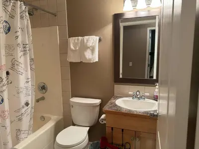 a bathroom with a toilet and a sink and a mirror at Heavenly Cozy Place Inc in Airdrie