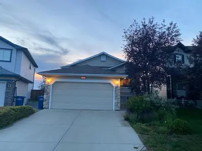 a house with a garage with lights on it at Heavenly Cozy Place Inc in Airdrie