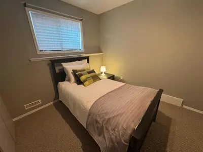 a bedroom with a large bed with a window at Heavenly Cozy Place Inc in Airdrie