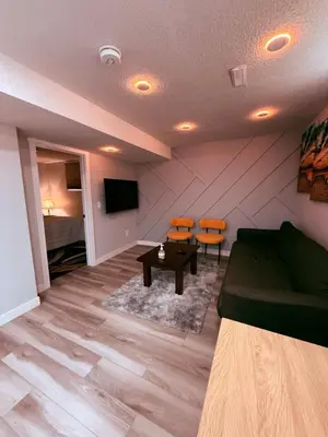 a living room with a couch and a table and chairs at Spacious 2 bedroom 3 beds lower unit with separate entrance and parking space Near Downtown, Calgary Zoo, Costco and many more in Calgary