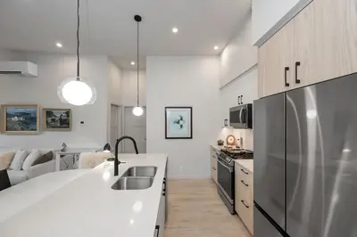 a kitchen with a sink and a refrigerator at Whirlaway – Luxurious one bedroom Penthouse with study and 2 parking spots by Victoria Prime! in Victoria