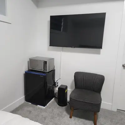 a room with a chair and a microwave and a television at Studio Suite in Northeast, Edmonton in Edmonton
