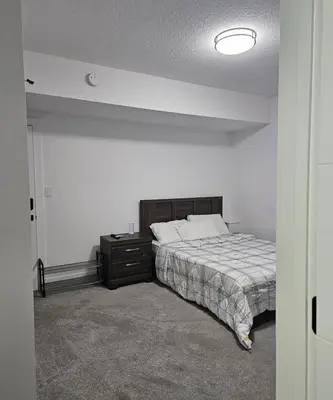 a bedroom with a bed and a nightstand with a bed sidx sidx sidx sidx at Studio Suite in Northeast, Edmonton in Edmonton