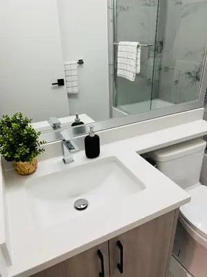 a white bathroom with a sink and a shower at New and Modern 1 bedroom suite near beach in Surrey