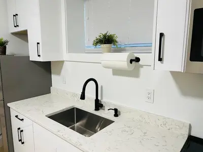 a white kitchen with a sink and a window at New and Modern 1 bedroom suite near beach in Surrey