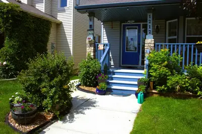 a house with a blue door and some plants at Entire suite Queen BRM Big Window Prvt Entry Patio in Edmonton