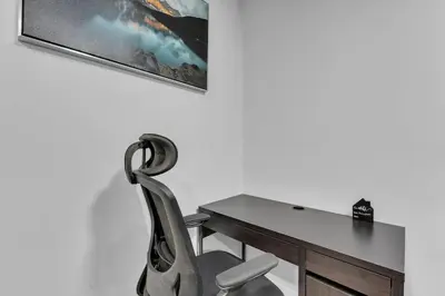 a chair next to a desk with a picture on the wall at TheCozyNest in Calgary