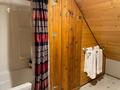 a bathroom with a wooden wall with a tub and towels at Luna Bed & Breakfast in Grand Forks