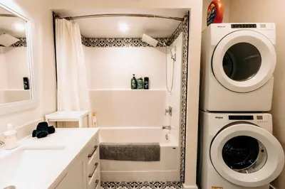 a bathroom with a washing machine next to a sink at Revy To Go - Unique 2-Bedroom Condo in Revelstoke